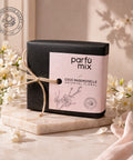 Parfum mix Coco Mademoiselle Oriental Floral candle with black box on a marble surface with flowers in the background