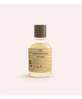 Perfume bottle with a label on a light pink background